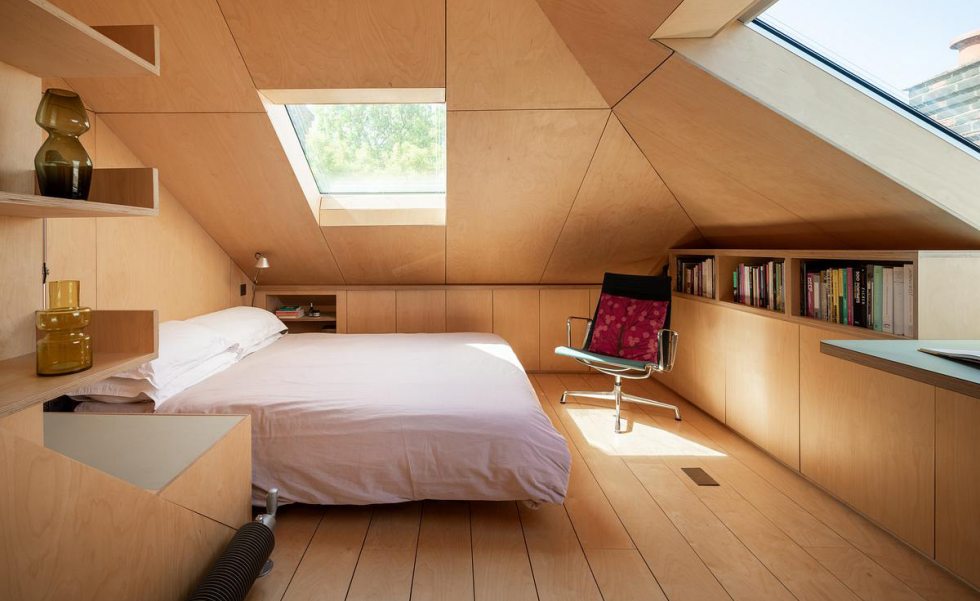 Sótão transformado em quarto com teto inclinado, marcenaria integrada e janelas de cobertura.