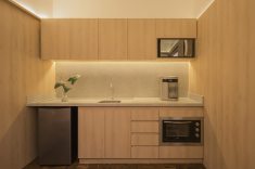 A iluminação indireta sob os armários e a marcenaria limpa eliminam os reflexos e o excesso de estímulos visuais na hora das refeições.