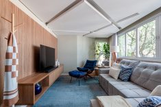 Design Nacional: A clássica Poltrona Costela, ícone do design modernista brasileiro, ocupa um ponto estratégico ao lado do sofá principal, reforçando o conforto.