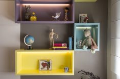 Fitas de LED embutidas nos nichos coloridos destacam os objetos decorativos sem criar pontos de ofuscamento no ambiente. Projeto de Luciana Ballio. Foto Emerson Rodrigues