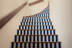 Os espelhos da escada receberam adesivagem de alta resistência com listras azuis transformando a circulação em um elemento gráfico.