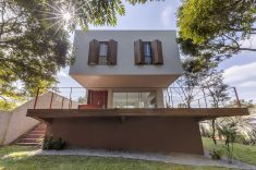 Nos fundos, o volume elevado acompanha o declive do terreno e se abre para o jardim.